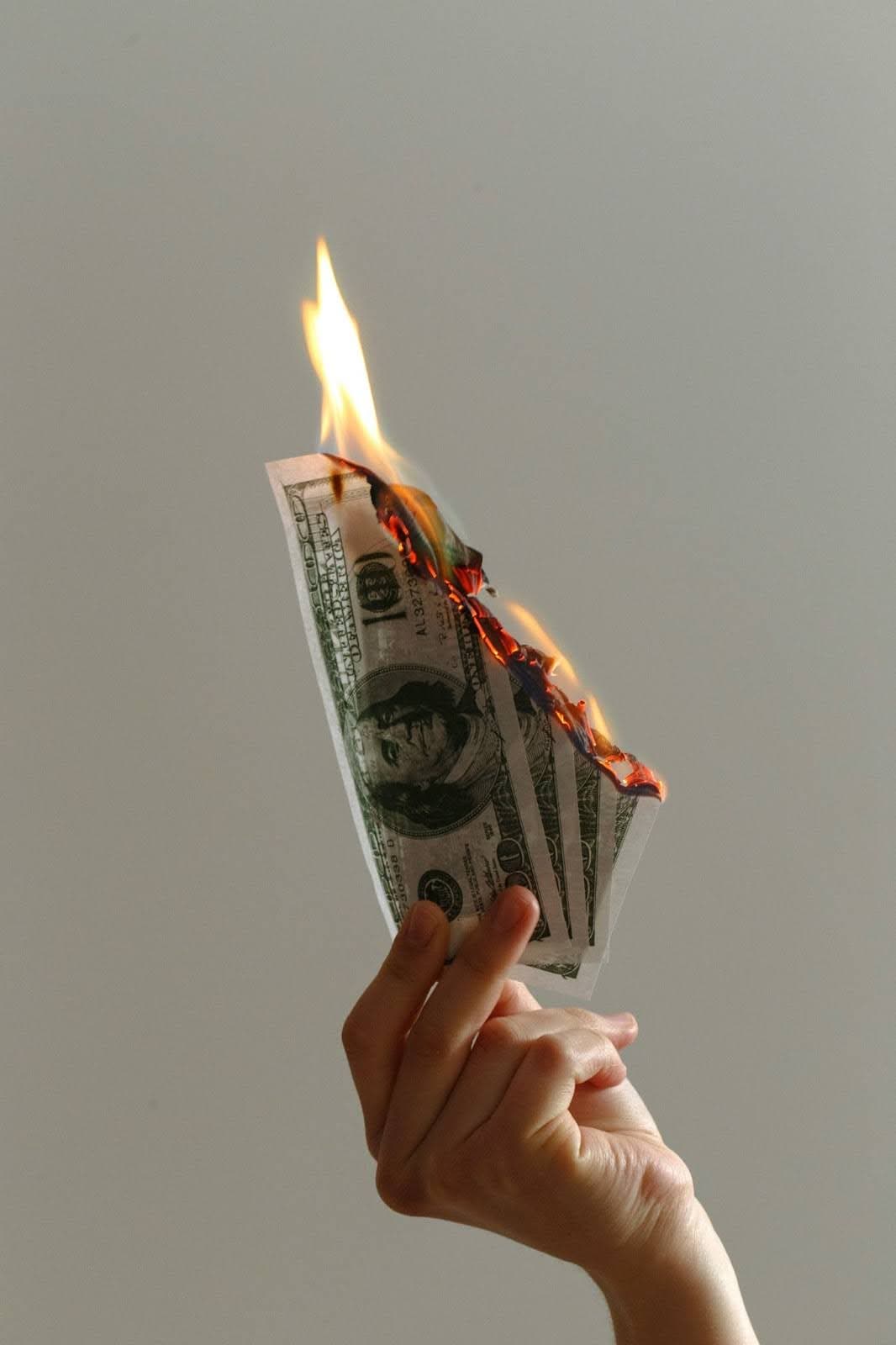 Person holding lighted dollar bills photo